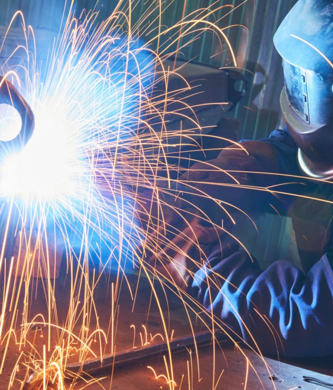 industrial welder worker at arc welding process with sparks. Focus on sparkle